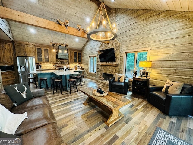 living room with beam ceiling, high vaulted ceiling, a stone fireplace, wooden ceiling, and light wood-type flooring