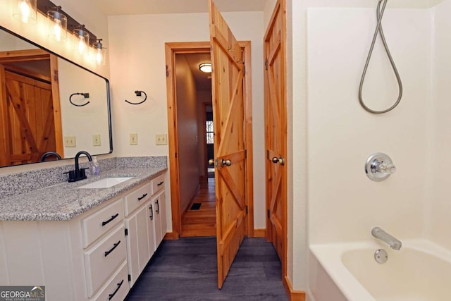 bathroom featuring shower / washtub combination, hardwood / wood-style floors, and vanity