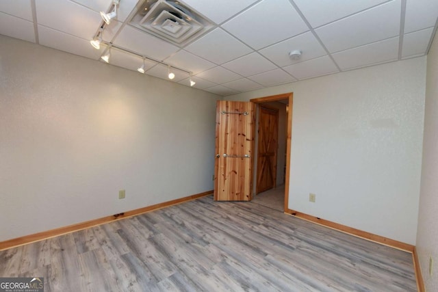 unfurnished room featuring track lighting, a drop ceiling, and light wood-type flooring