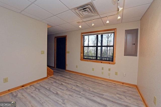 spare room featuring a paneled ceiling, rail lighting, electric panel, and light hardwood / wood-style flooring