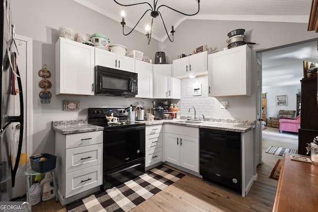 kitchen featuring sink, vaulted ceiling, black appliances, and white cabinets