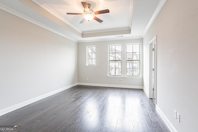 empty room with crown molding, a tray ceiling, dark hardwood / wood-style floors, and ceiling fan