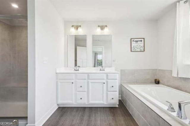 bathroom featuring vanity, tiled bath, and hardwood / wood-style floors