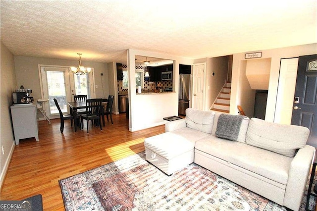 living room with wood-type flooring, a notable chandelier, and a textured ceiling