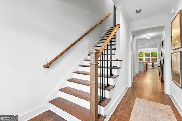 stairway featuring crown molding and hardwood / wood-style flooring