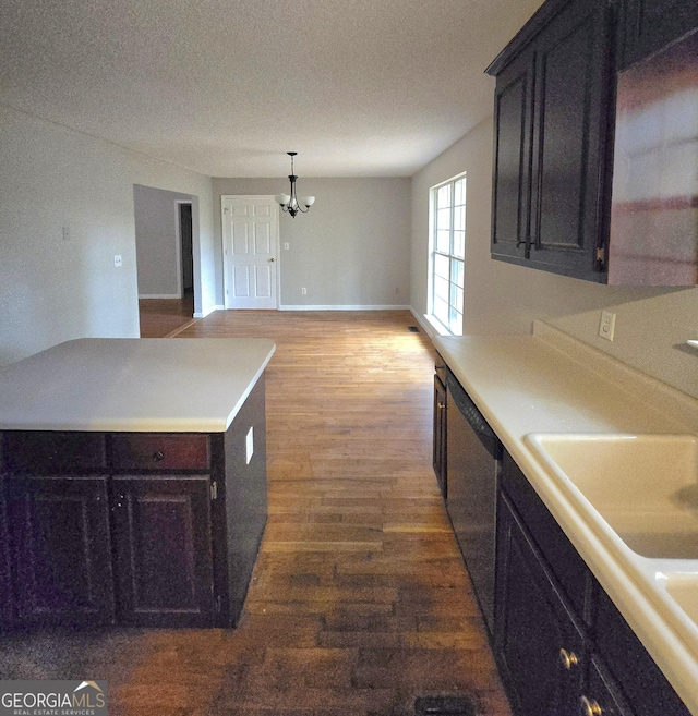 kitchen with hardwood / wood-style floors, dishwasher, sink, hanging light fixtures, and an inviting chandelier