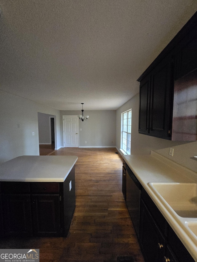 kitchen featuring pendant lighting, dark hardwood / wood-style floors, stainless steel dishwasher, and a textured ceiling