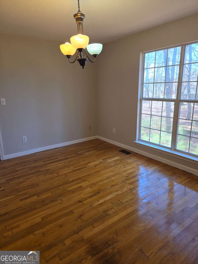 empty room featuring dark hardwood / wood-style floors and a notable chandelier