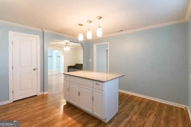 kitchen featuring white cabinetry, hanging light fixtures, light wood-type flooring, ornamental molding, and a kitchen island