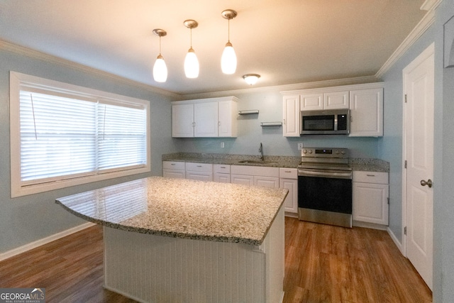 kitchen with decorative light fixtures, white cabinetry, sink, stainless steel appliances, and crown molding