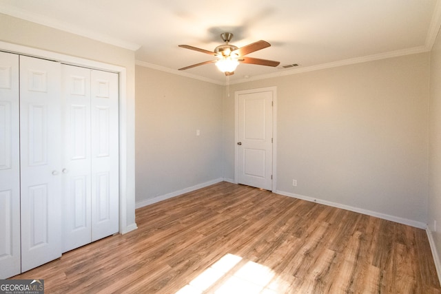 unfurnished bedroom featuring crown molding, ceiling fan, a closet, and light hardwood / wood-style flooring