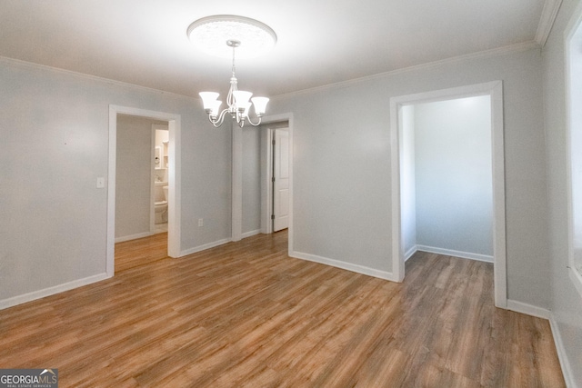 empty room featuring ornamental molding, hardwood / wood-style floors, and a notable chandelier