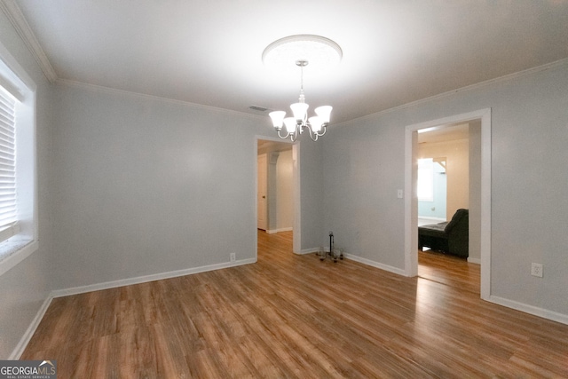 empty room with crown molding, hardwood / wood-style floors, and a notable chandelier