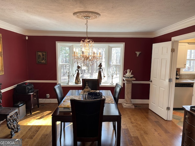 dining space with crown molding, hardwood / wood-style floors, a textured ceiling, and a chandelier