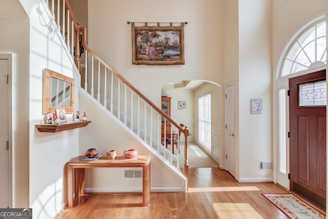 entryway with a towering ceiling and light hardwood / wood-style flooring