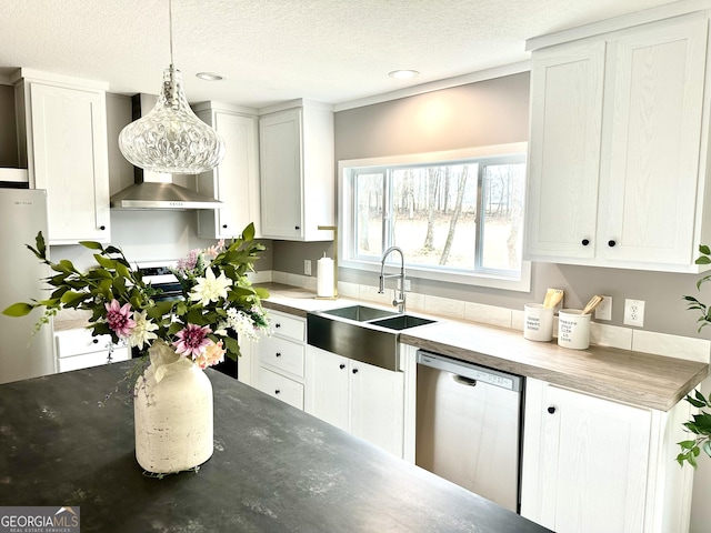 kitchen with pendant lighting, wall chimney range hood, sink, stainless steel appliances, and white cabinets