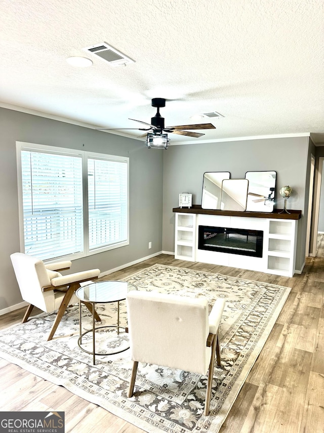 living room featuring crown molding, hardwood / wood-style floors, a textured ceiling, and ceiling fan