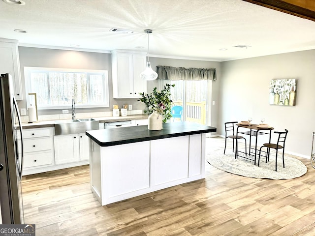 kitchen featuring sink, stainless steel refrigerator, a center island, and white cabinets