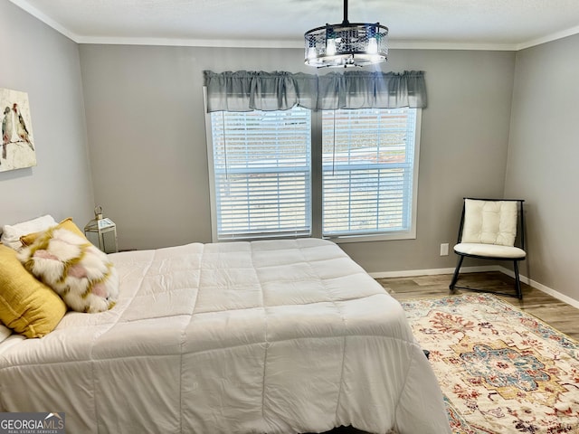 bedroom with hardwood / wood-style flooring, crown molding, and a chandelier