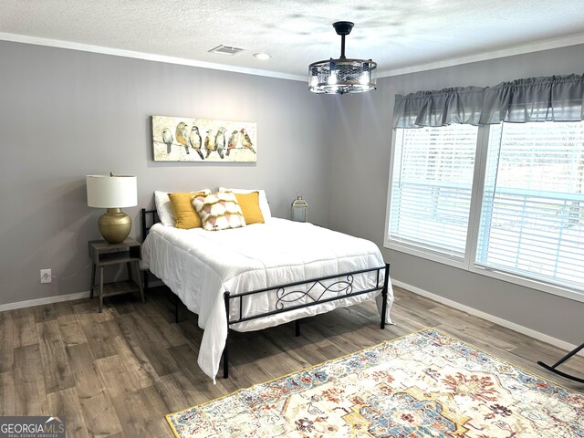 bedroom with multiple windows, crown molding, hardwood / wood-style flooring, and a textured ceiling