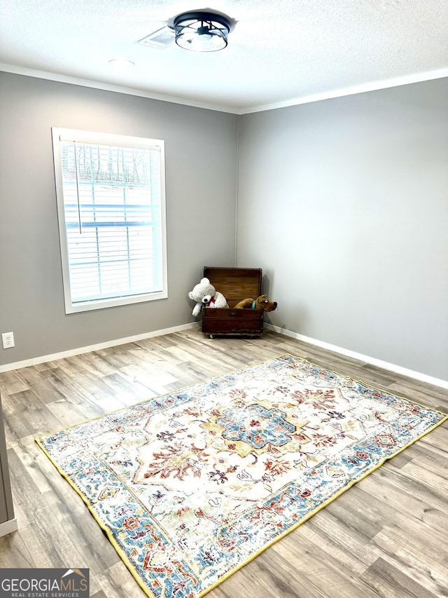 living area with ornamental molding, wood-type flooring, and a textured ceiling