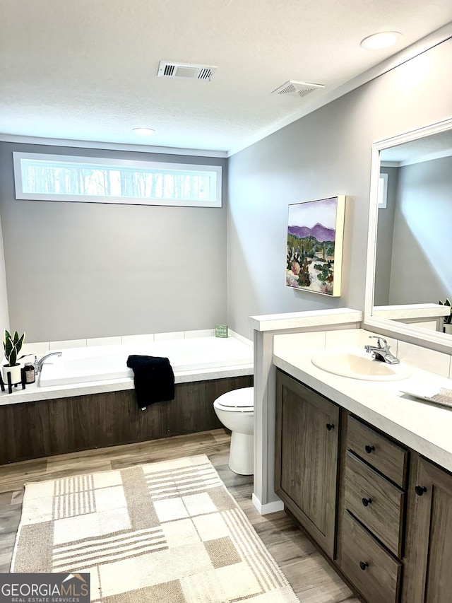 bathroom with vanity, hardwood / wood-style flooring, a bathing tub, and toilet