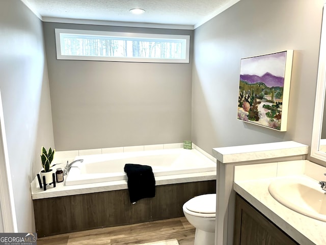 bathroom with toilet, a textured ceiling, vanity, a tub, and hardwood / wood-style flooring