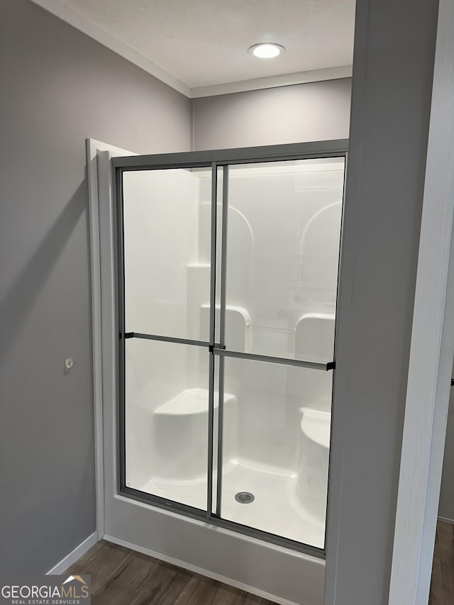 bathroom with wood-type flooring and a shower with shower door