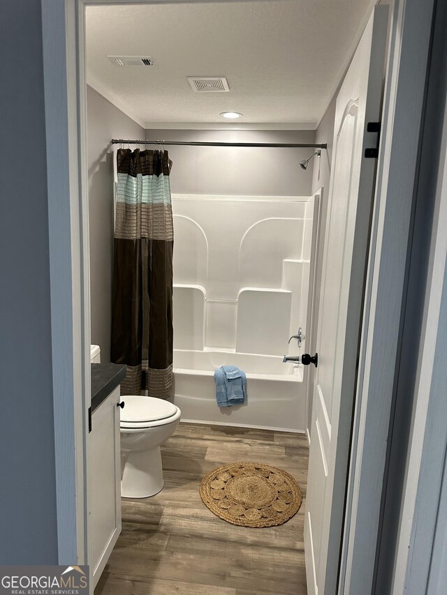 full bathroom with wood-type flooring, toilet, vanity, and shower / bath combo with shower curtain