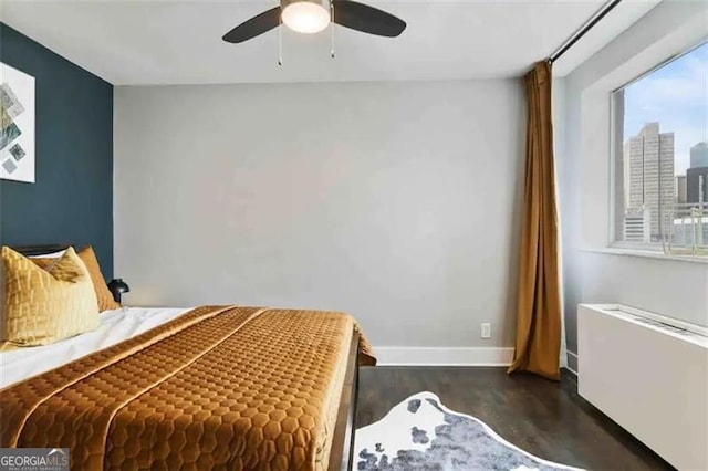 bedroom featuring ceiling fan, radiator heating unit, and dark hardwood / wood-style flooring