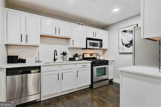 kitchen featuring sink, dark hardwood / wood-style floors, white cabinets, stainless steel appliances, and backsplash