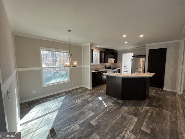 kitchen with dark hardwood / wood-style flooring, hanging light fixtures, a center island, stainless steel appliances, and crown molding