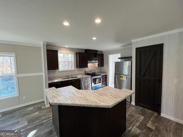 kitchen with appliances with stainless steel finishes, sink, a center island, dark brown cabinetry, and dark wood-type flooring