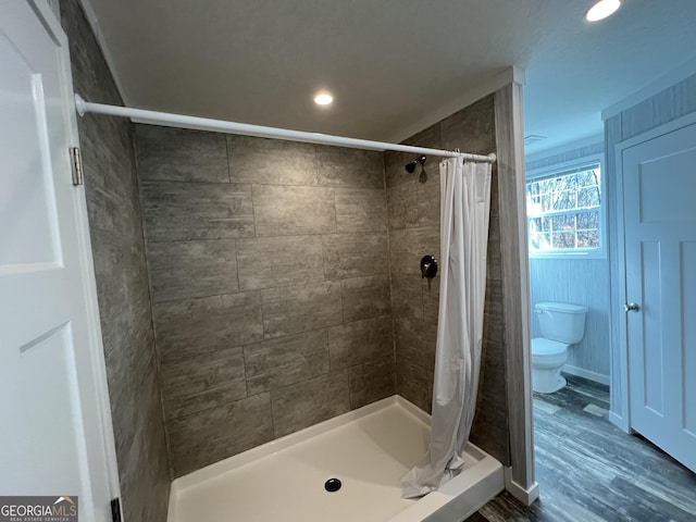 bathroom with wood-type flooring, toilet, and curtained shower