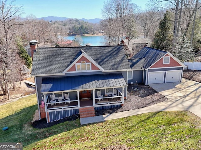 view of front of house with a garage, a water and mountain view, a front yard, and covered porch