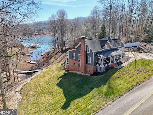 exterior space with covered porch, a lawn, and a water view