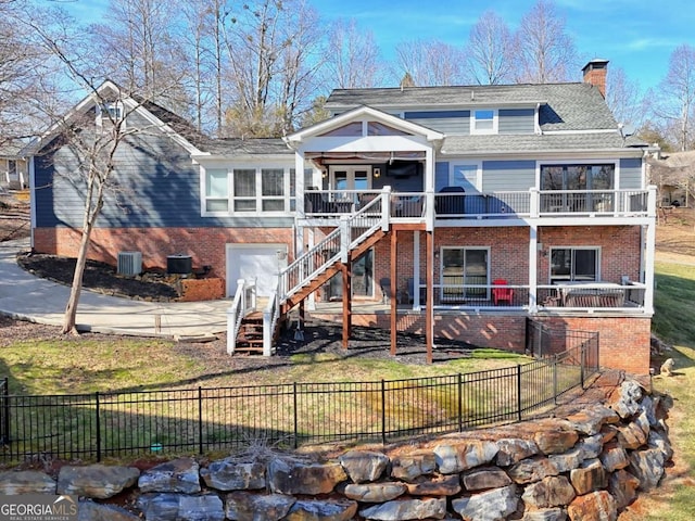 back of property featuring a garage, a lawn, and a balcony