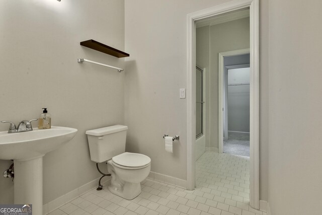 full bathroom featuring bath / shower combo with glass door, sink, toilet, and tile patterned flooring