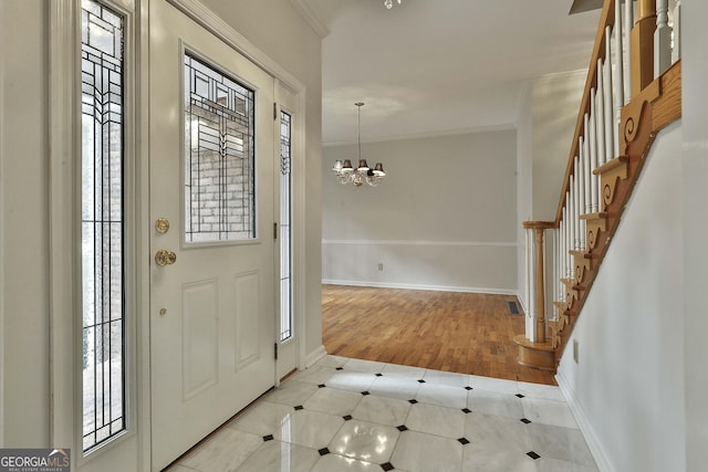 foyer entrance with crown molding and a chandelier