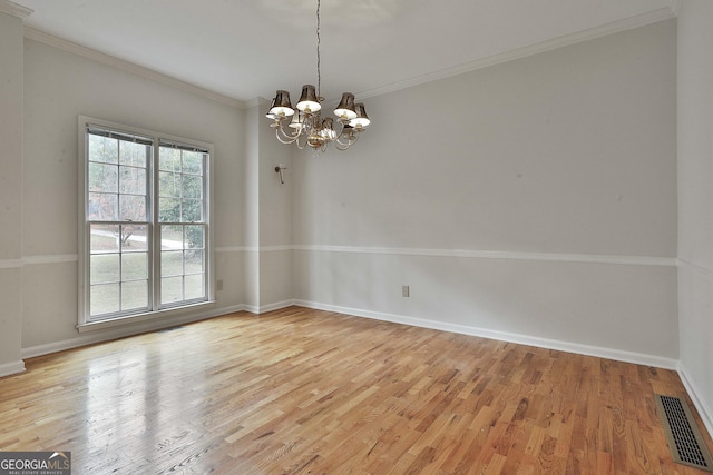 empty room featuring ornamental molding, an inviting chandelier, and light wood-type flooring