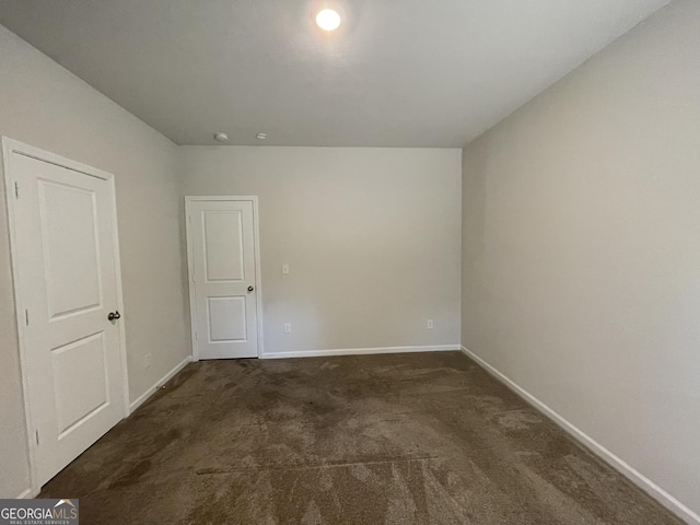 spare room with dark colored carpet