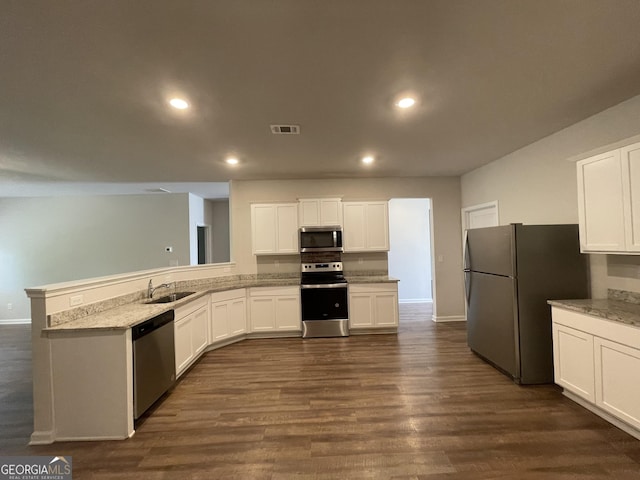 kitchen with sink, white cabinets, stainless steel appliances, light stone countertops, and dark wood-type flooring