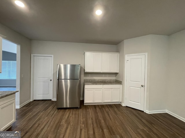 kitchen with dark wood-type flooring, stainless steel fridge, and white cabinets