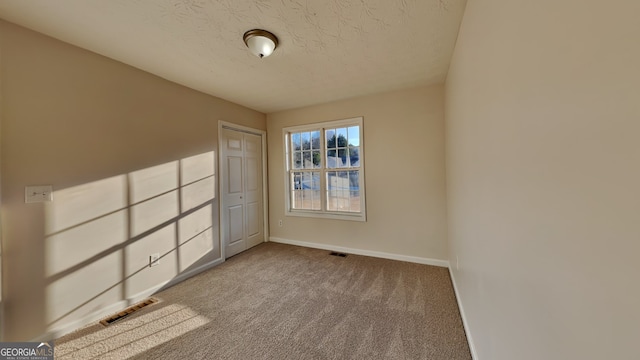 unfurnished bedroom with a closet, light carpet, and a textured ceiling