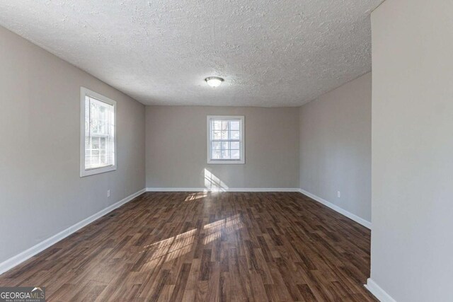 unfurnished room featuring a textured ceiling and dark hardwood / wood-style flooring