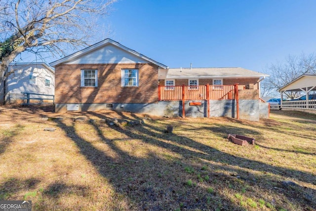 back of property with a wooden deck and a yard