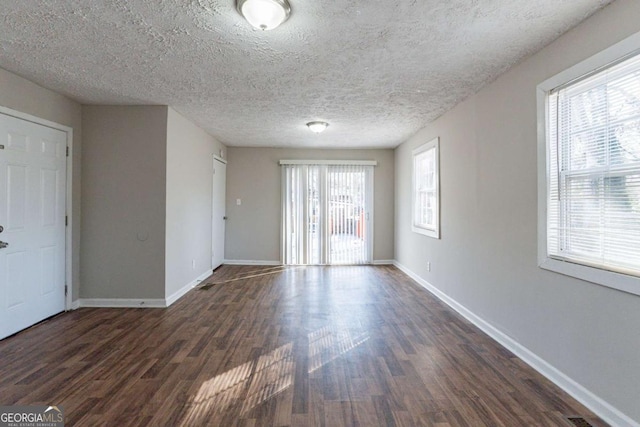 empty room with dark hardwood / wood-style floors and a textured ceiling