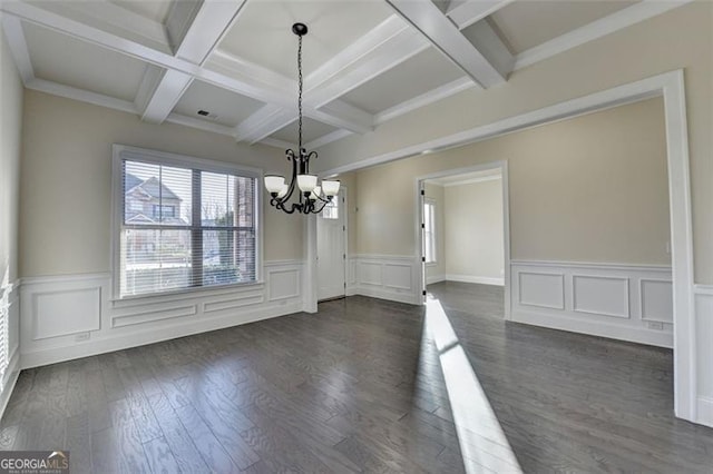 unfurnished dining area featuring beamed ceiling, coffered ceiling, dark hardwood / wood-style floors, and an inviting chandelier