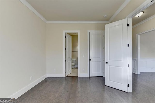 unfurnished bedroom featuring ornamental molding, dark hardwood / wood-style floors, and connected bathroom