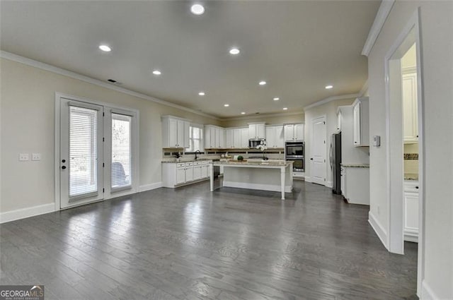 kitchen featuring white cabinetry, stainless steel appliances, dark hardwood / wood-style floors, ornamental molding, and a kitchen island